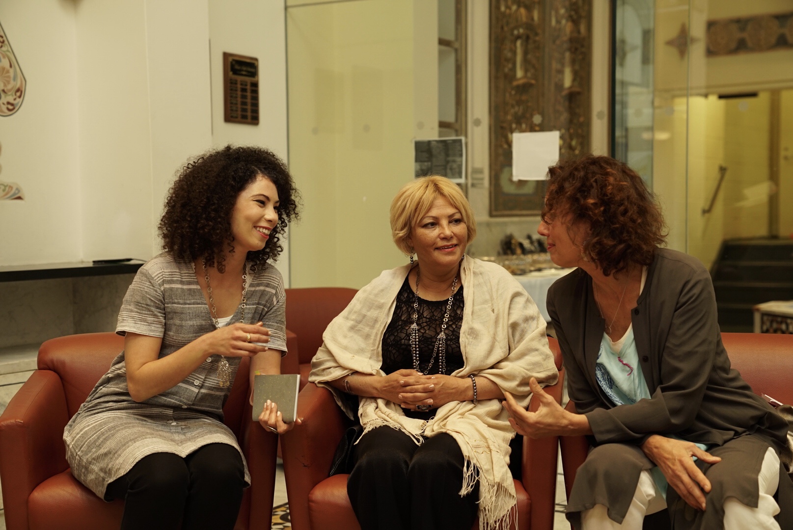 Three women sit smiling and talking to one another
